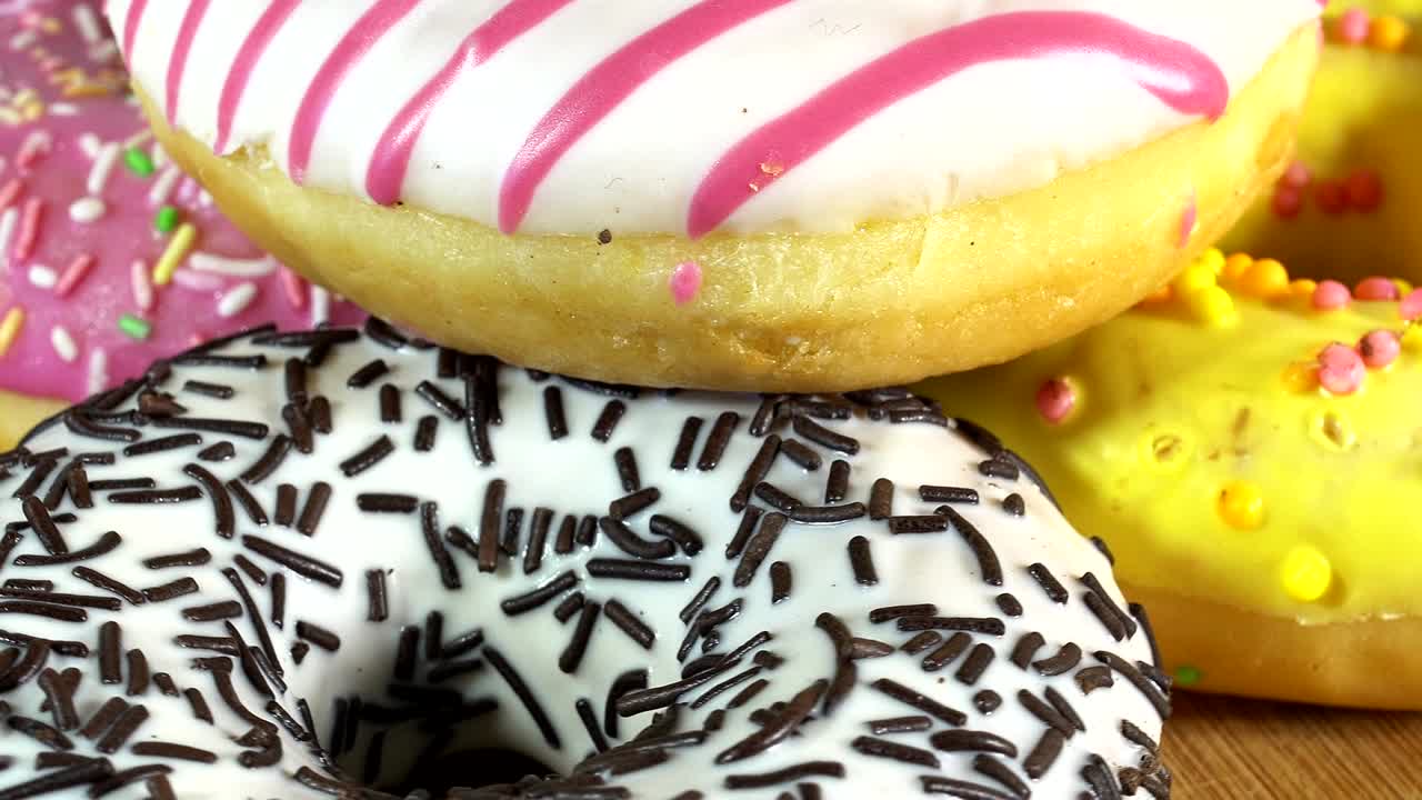 rosquillas giratorias con diferentes rellenos en la mesa. deliciosa rosquilla dulce girando en un plato. rosquilla brillante y colorida macro disparo de primer plano girando sobre un fondo blanco. bucle sin costuras.