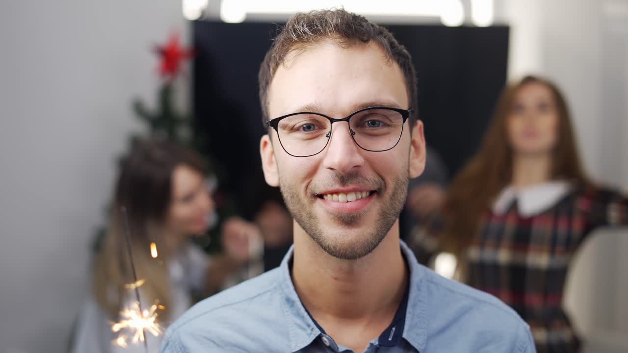joven empresario en una fiesta de la compañía con un palo brillante, sonriendo a la cámara