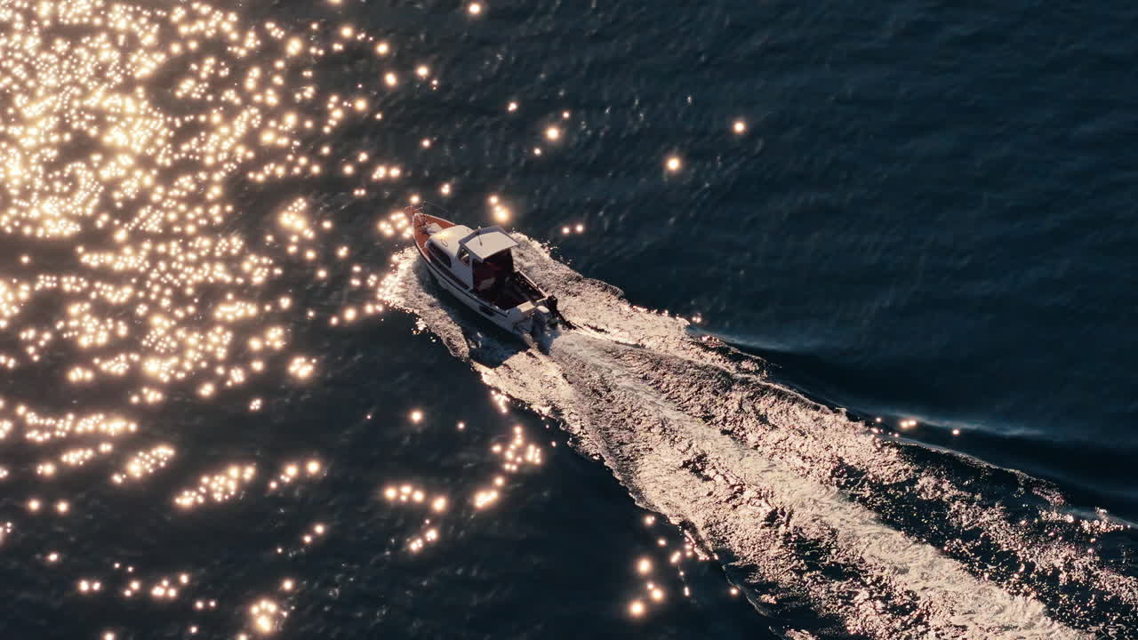 Aerial drone view of a small motorboat speeding across the water, leaving a white foamy trail behind it on the calm turquoise sea. Biograd na Moru, Croatia