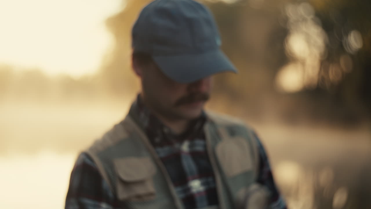 Man with a mustache in a baseball cap, profile view, outdoors at sunrise