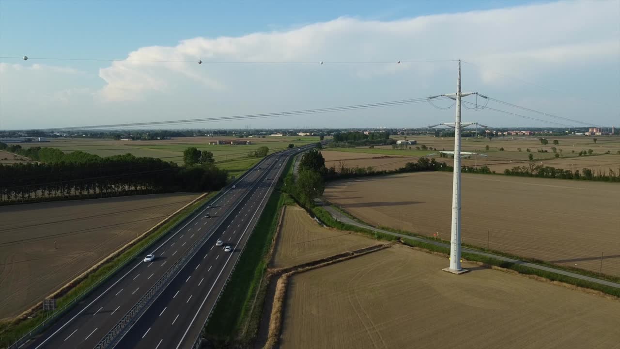 view from the drone of a new light pylon for the passage of high voltage electricity in countryside landscape and traffic car highway - increase in the cost of electricity energy  and green revolution