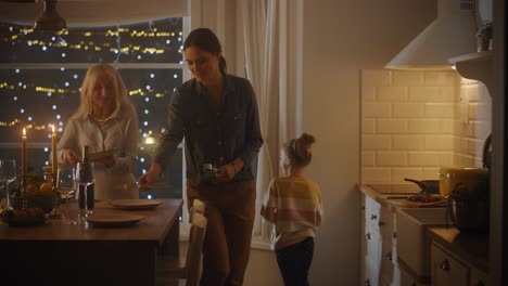 varias generaciones de mujeres hermosas preparando y sirviendo la cena en la cocina. abuela, hija y nieta linda se divierten, cocinando juntos, hablando, compartiendo secretos y recetas