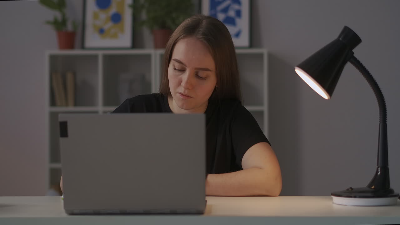 mujer está estudiando en línea escribiendo notas en casa por la noche sentada en la mesa fotografía panorámica alrededor de su medio retrato de estudiante de aprendizaje