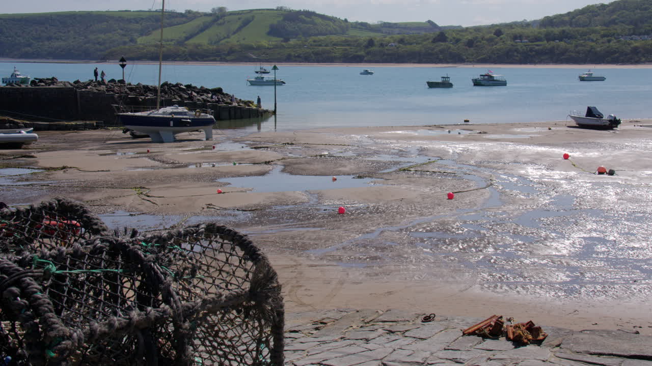 Wide shot of new quay harbour at low tide with Lobster pots in foreground