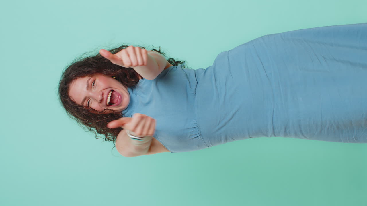 Young woman raises thumbs up agrees or gives positive reply recommends advertisement likes good idea