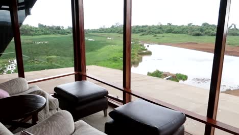 panning shot from inside a safari resort hotel looking out onto a fresh river