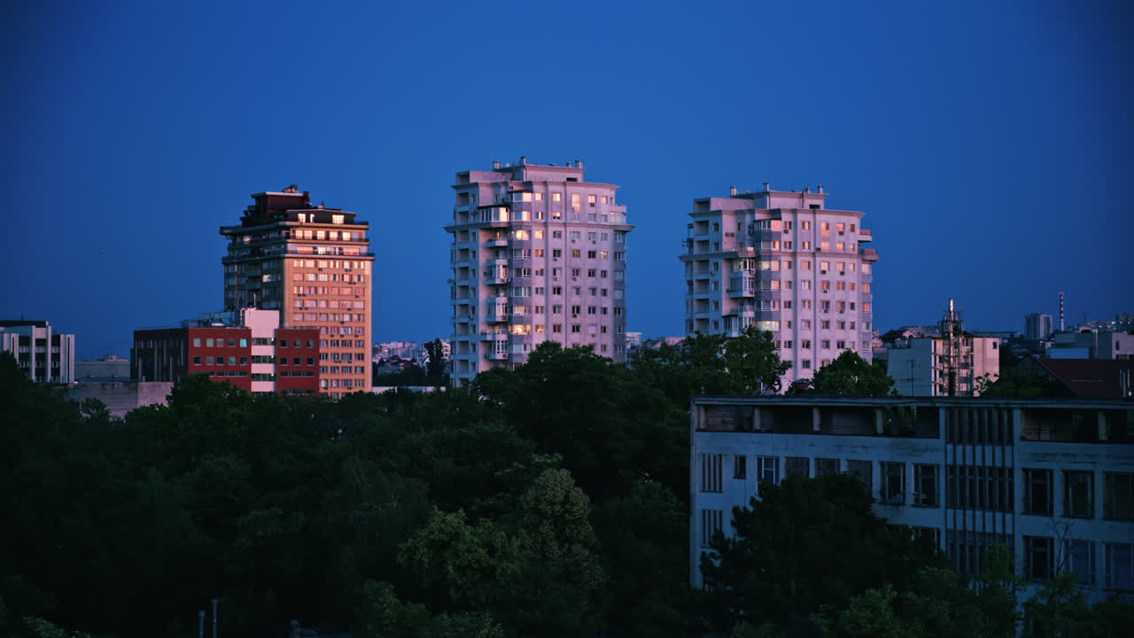 Tall buildings surrounded by green trees with the sky on the background in Chisinau, Moldova in the evening