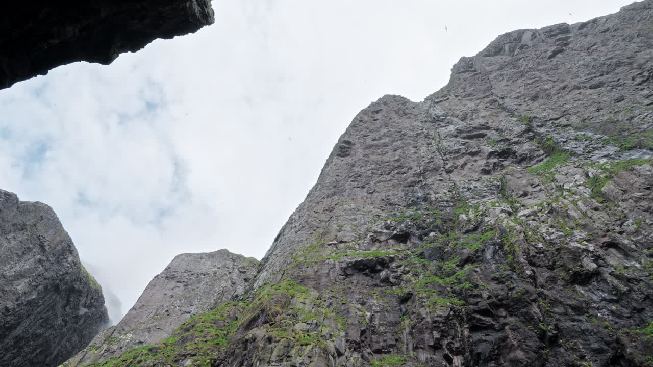 A majestic rocky cliffside in the Faroe Islands, featuring steep terrain and greenery