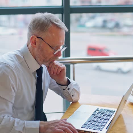 Businessman wears neatly white shirt and drinking coffee near big window with city view looking away.