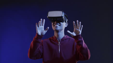 homem asiático usando fone de ouvido vr, tocando tela virtual em fundo azul, câmera lenta