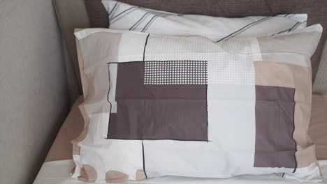 almohada de patrón geométrico beige y marrón en la cama