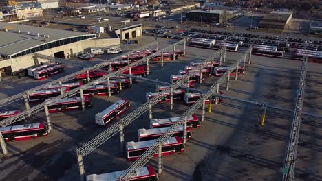 TTC public transit buses at large operations, maintenance and storage facility as multiple buses drive through parking lot