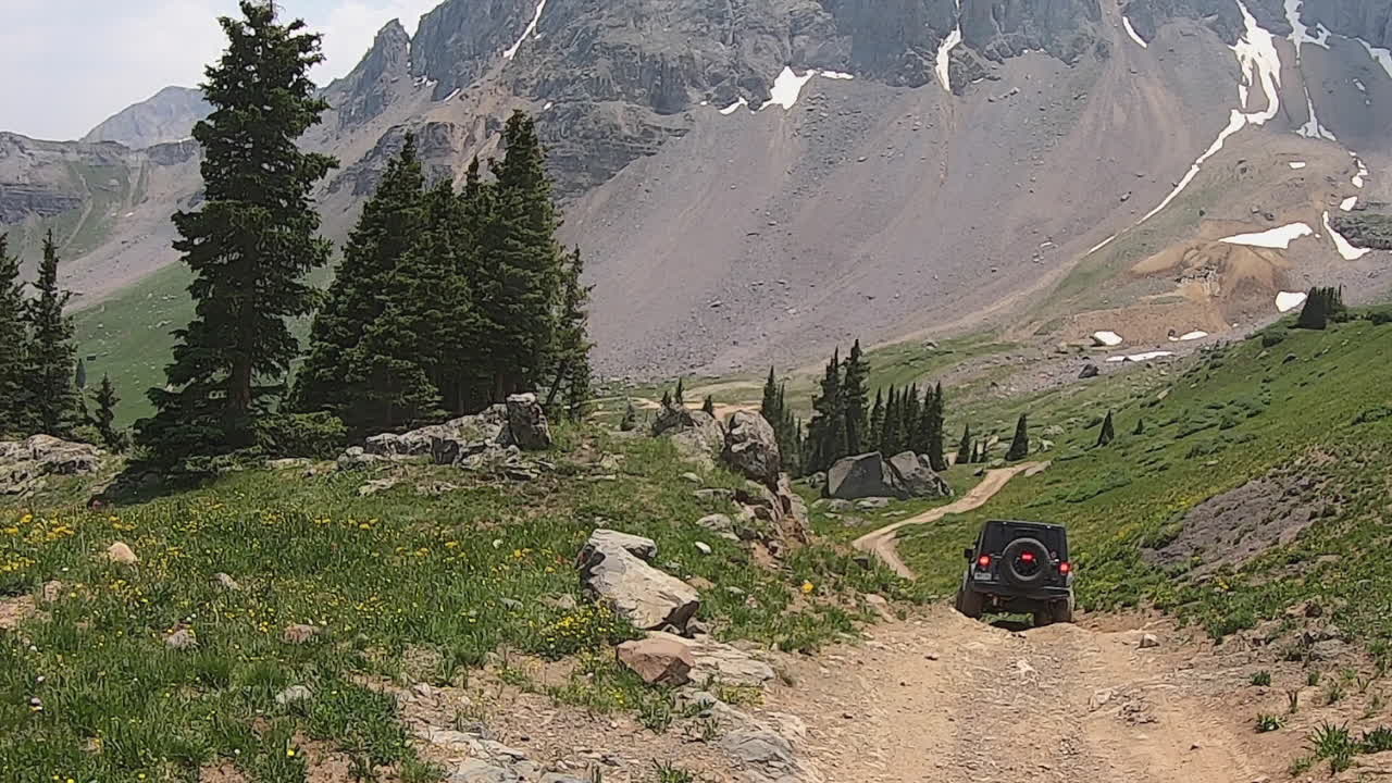 Et firehjulsdrevet kjøretøy kjører sakte langs den steinete delen av Sidney Basin Loop Trail i Yankee Boy Basin i San Juan-fjellene i Colorado.