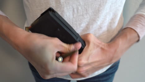 Closeup-of-woman-struggling-to-load-a-AR-15-magazine-with-bullets