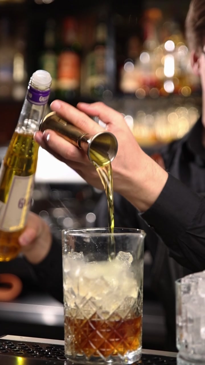 Barman professionista che misura e versa liquore in un bicchiere da cocktail