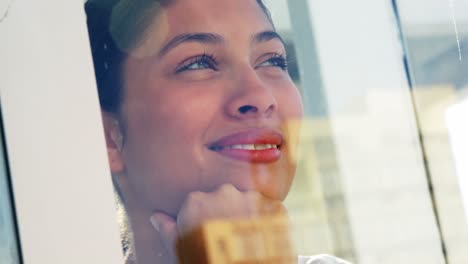 mujer sonriente mirando por la ventana de la oficina