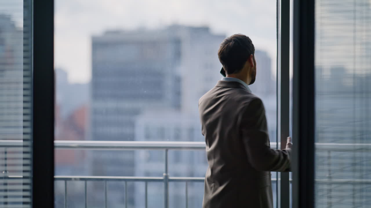 Worried ceo calling phone strolling near office window closeup. Nervous manager