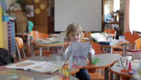 mädchen zieht am tisch im klassenzimmer. bildung. kind sitzt an einem schreibtisch