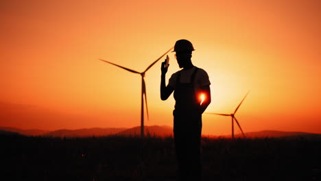 silhouette of engineer at wind farm sunset