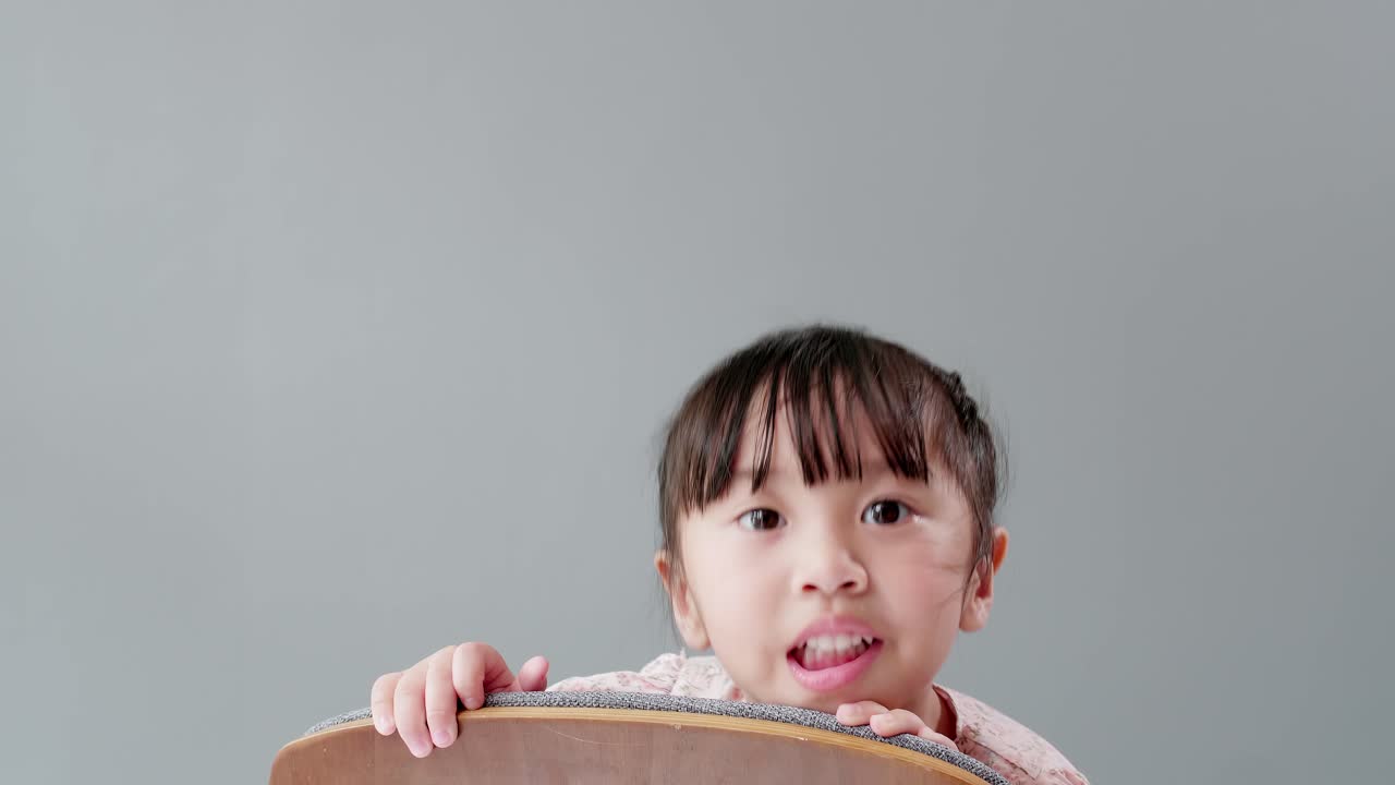 의자 미소에 앉아 방에서 행복을 애타게 하는 귀여운 아시아 소녀