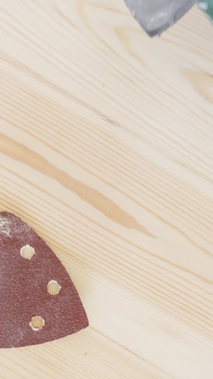 Close-up of a person replacing sandpaper on a detail sander during a DIY project