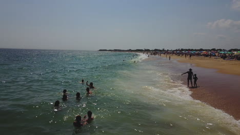 drone panorámica hacia adelante toma del océano con las olas rompiendo y turistas en la playa