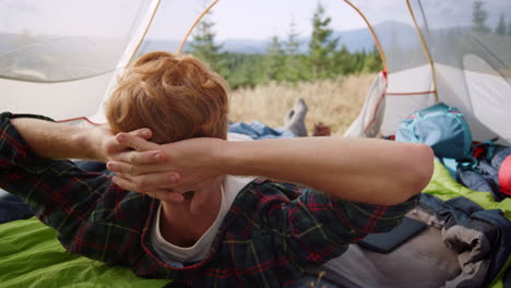 Man-lying-in-tent-during-hike-in-mountains