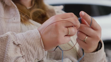 woman knitting with blue yarn in a cozy sweater in outdoor environment