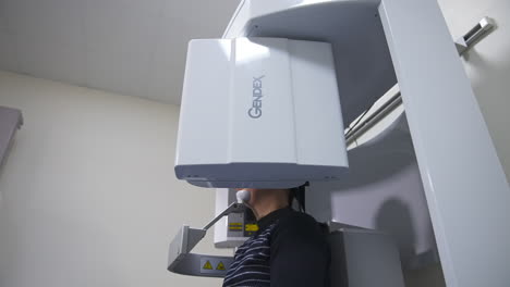 male patient sitting in the apparatus taking an x-ray shot of teeth. advanced equipment in modern dentist clinic. low angle view.