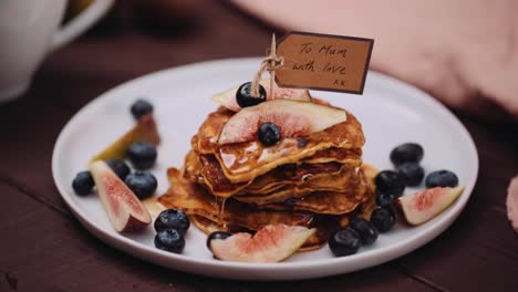 mothers day pancakes with pink rose served on the wooden table - a plate of pancakes with blueberries and maple syrup