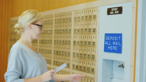 Una-Mujer-Joven-Con-Gafas-Arroja-Unas-Cartas-En-El-Buzón-De-La-Oficina-De-Correos