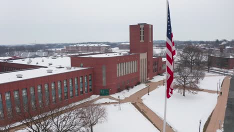 aerial establishing shot of large brick school building covered in snow during winter