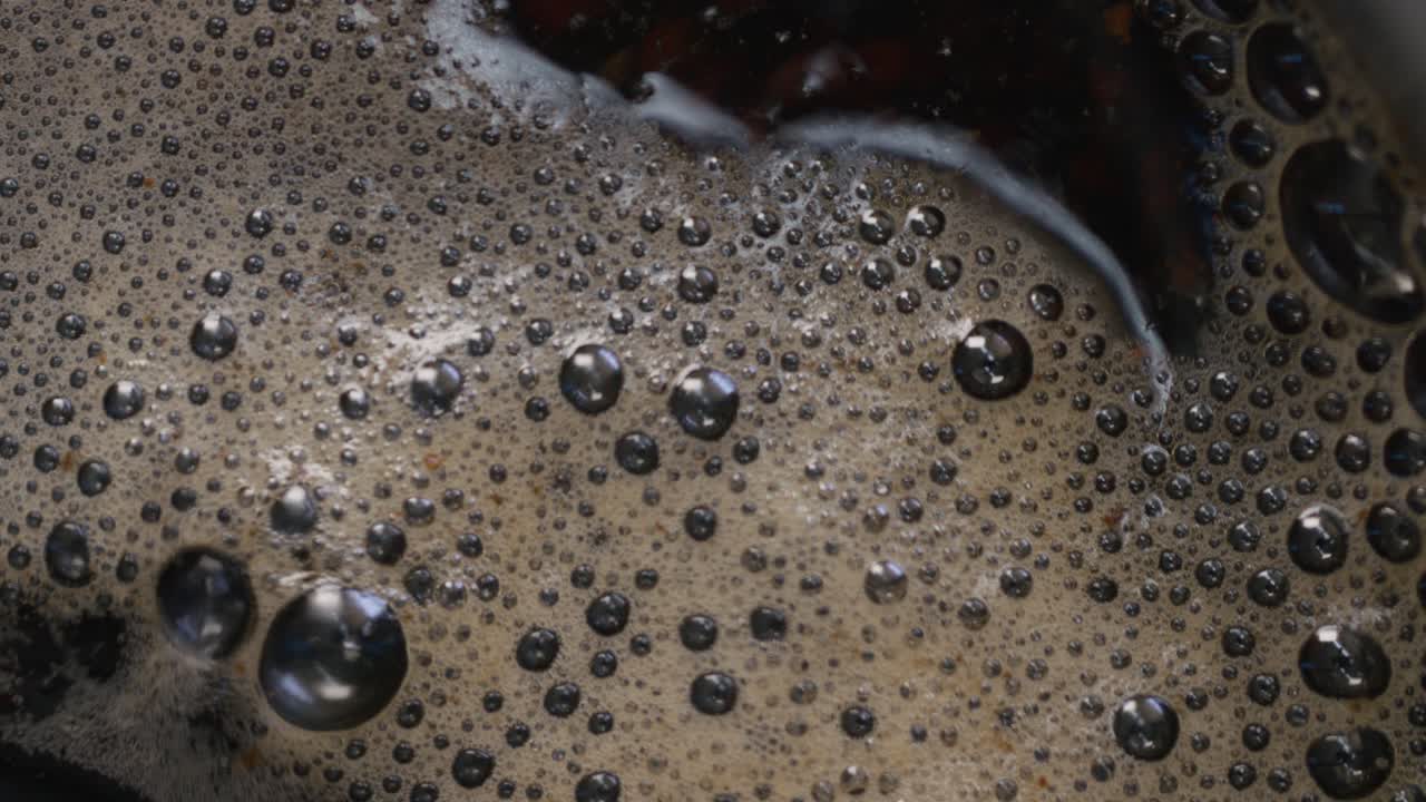 A detailed close-up, slow-motion of tea particles boiling in water with steam, preparing a hot drink