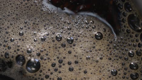 a detailed close-up, slow-motion of tea particles boiling in water with steam, preparing a hot drink