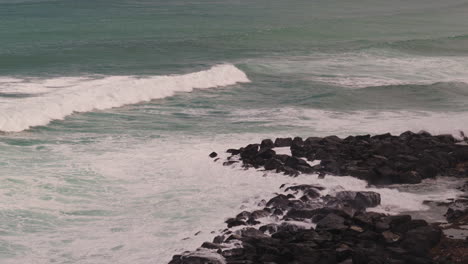 ocean waves crashing on dark rocks
