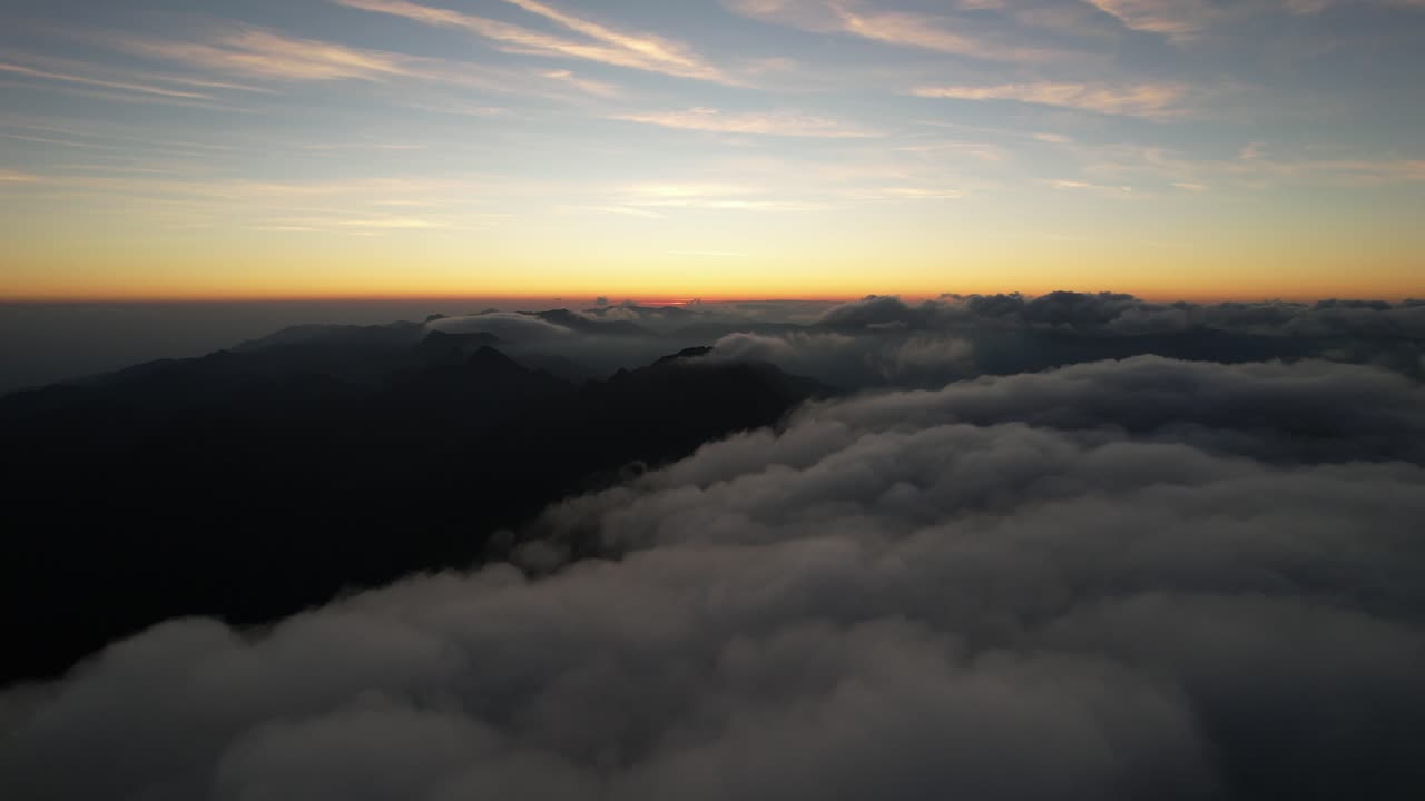 A serene sunrise over mountain peaks and clouds, evoking tranquility and wonder