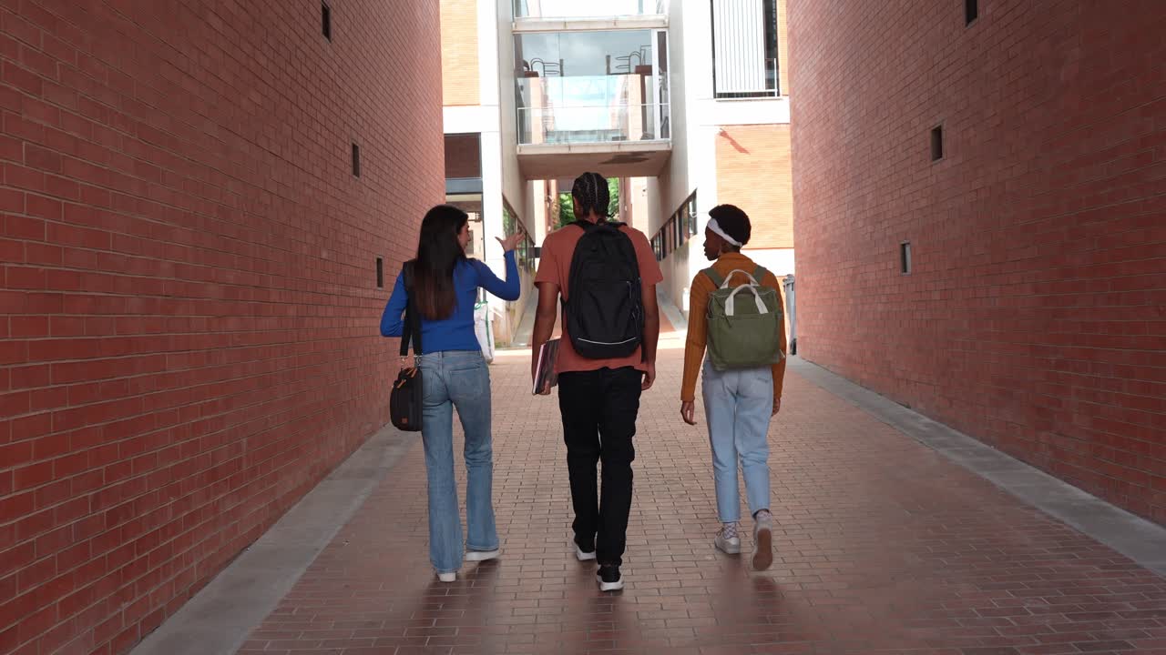 Tres jóvenes estudiantes caminando y conversando en un campus universitario