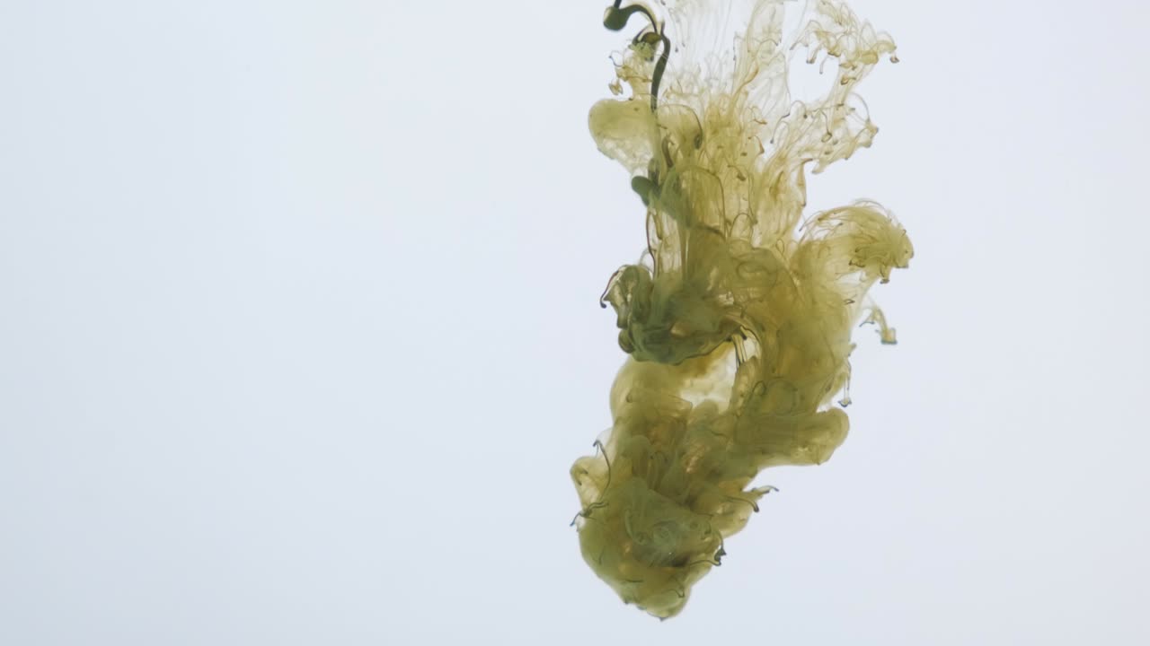 Green paint explodes and sprays in the water on a white background. Color abstraction