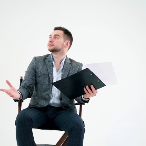 serious businessman holding a folder and reading documents. paper works flying over the handsome man in grey suit isolated on white studio background.