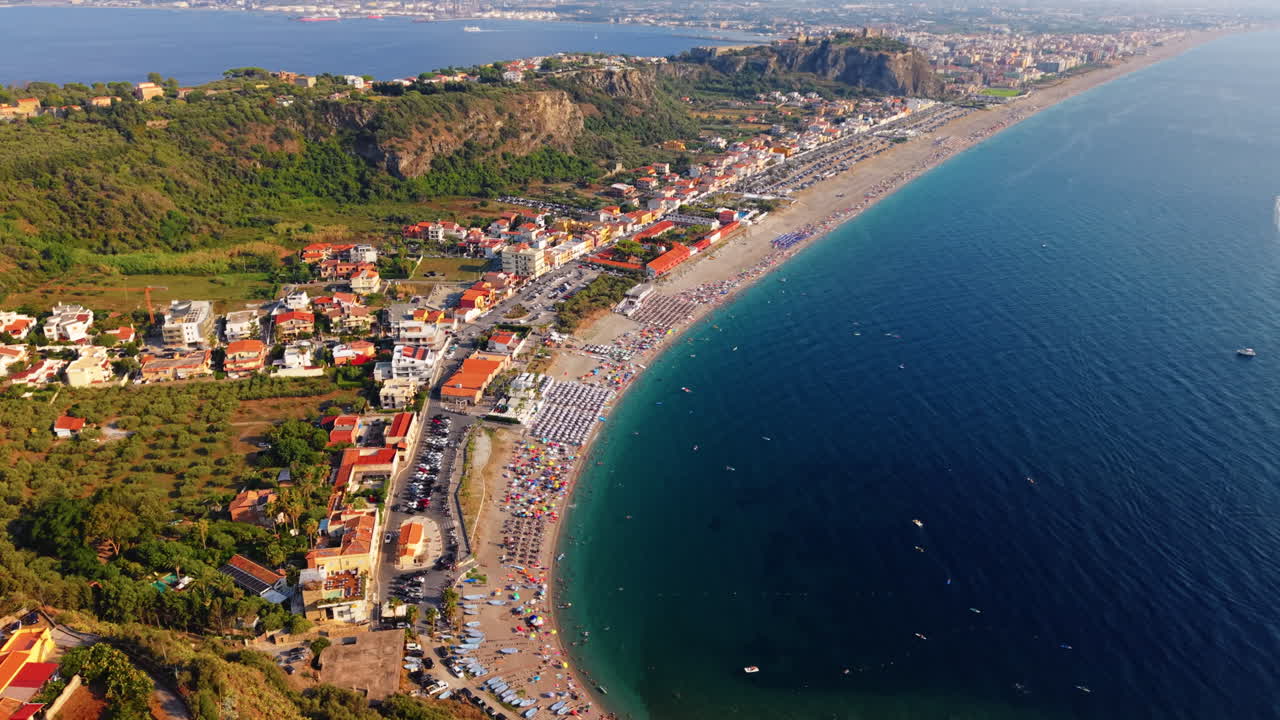 Vista aérea de uma cidade costeira com praia vibrante e colinas exuberantes