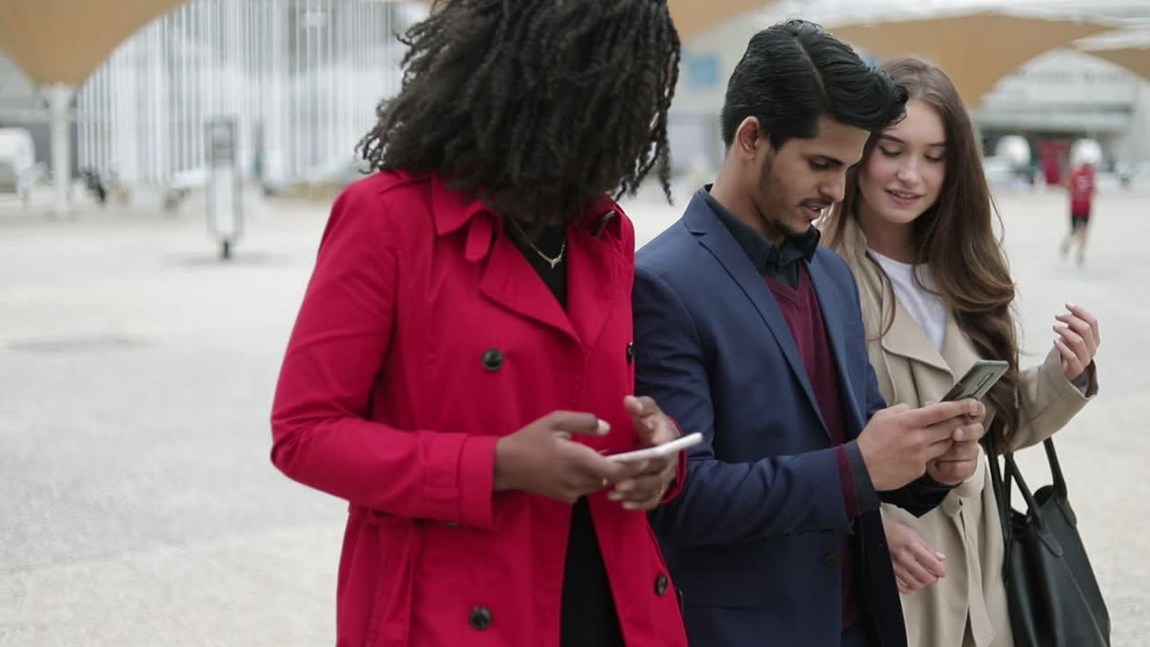 tres personas caminando por la calle, un hombre mostrando fotos en el teléfono