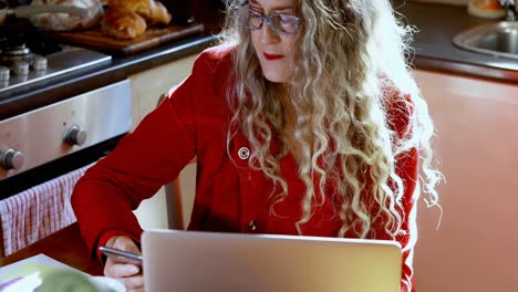 mujer madura usando teléfono móvil en la cocina 4k