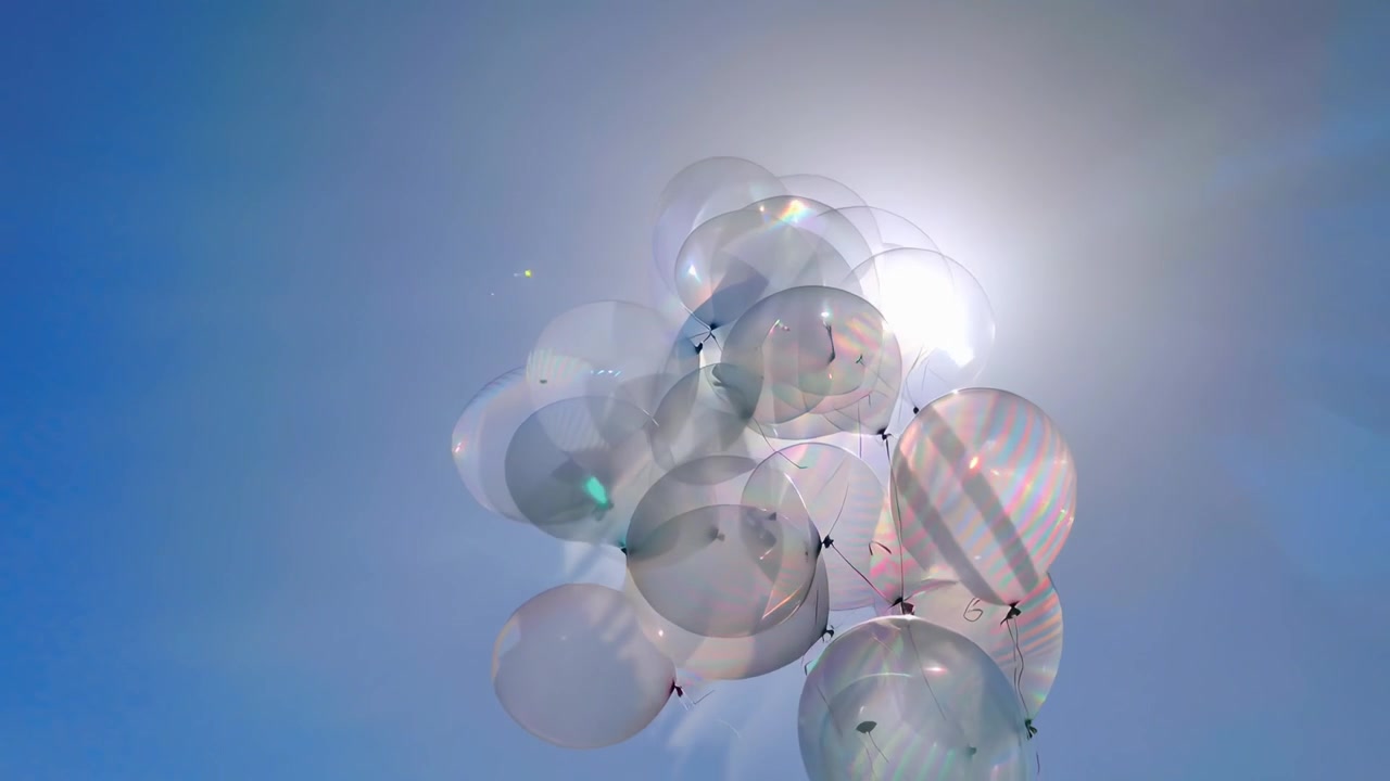 Schillernde transparente Ballons schweben vor strahlend blauem Himmel