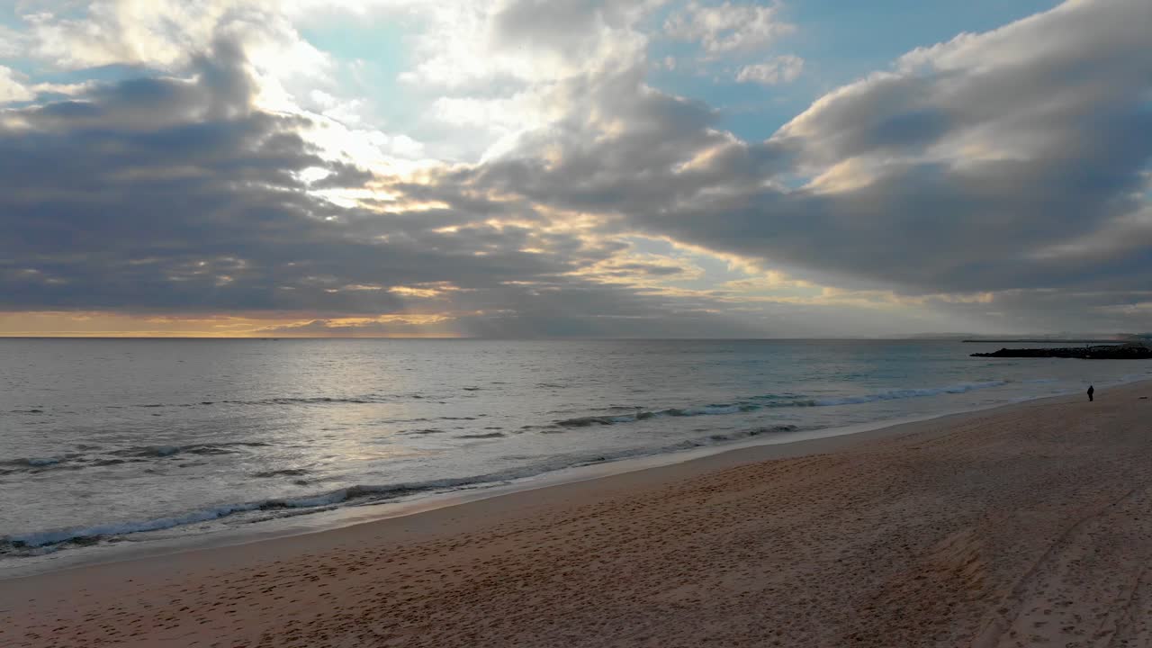 Tramonto con cielo nuvoloso e onde che si infrangono su una spiaggia in Portogallo.