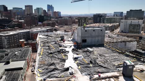 construction workers and crane working on rooftop of new building, aerial