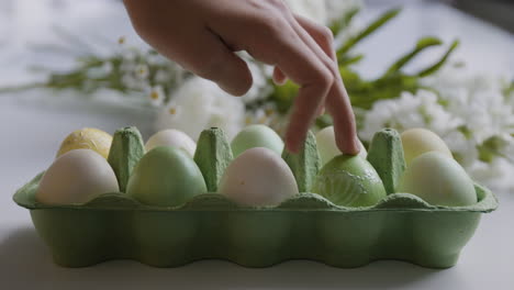 hand selecting easter egg from carton with flowers