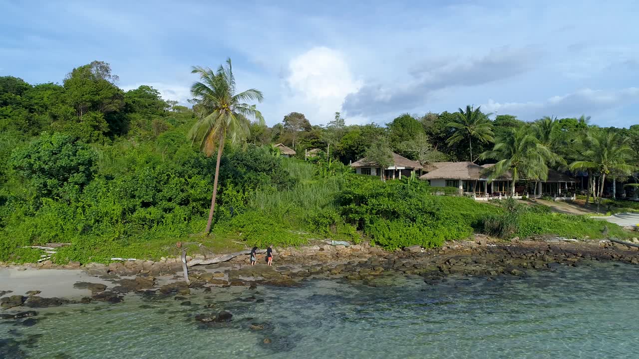 aéreo, disparo de drones, hacia personas que caminan en una playa paradisíaca, en un mar turquesa poco profundo, en un día cálido y soleado, en koh kood, tailandia, asia