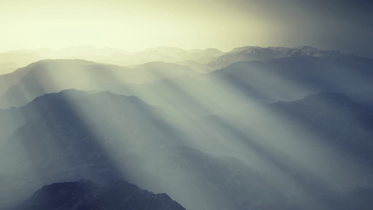 Mountain landscape with sunlight rays piercing through misty atmosphere