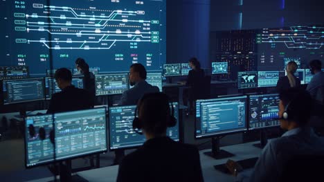 team of professional computer data science engineers work on desktops with screens showing charts, graphs, infographics, technical neural data and statistics. low key control and monitoring room.