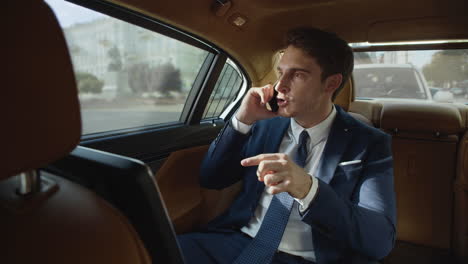 Strict-business-man-swearing-on-mobile-phone-in-back-seat-of-luxury-automobile.